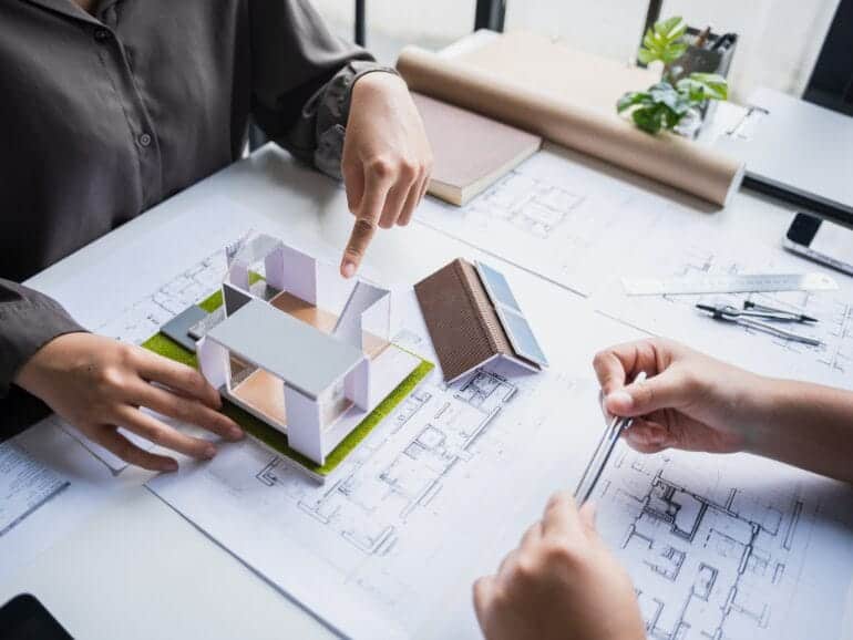 4-present-options-770x433 Two architects discussing a solar-powered house model on blueprints.